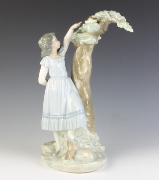 A Nao figure of a girl standing by a tree pointing at a birds nest 28cm 