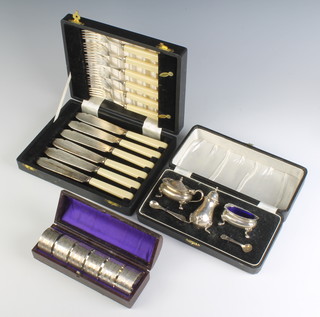 A silver condiment comprising salt, pepper and mustard with 2 spoons, cased Birmingham 1946 115 grams, 6 cased plated napkin rings and a cased set of fish eaters for 6 