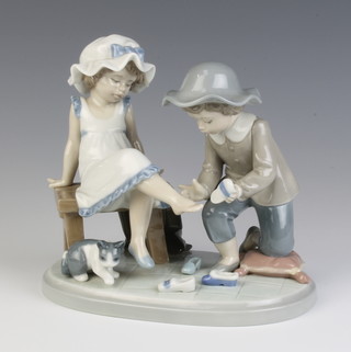 A Lladro group of a boy kneeling at the feet of a girl holding a slipper with a kitten 5361 15cm 