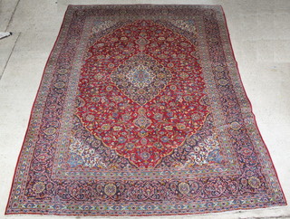 A red and floral patterned Persian rug with central medallion 399cm x 294cm 