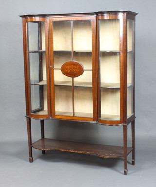 An Edwardian inlaid mahogany display cabinet, the interior fitted shelves enclosed by an astragal glazed panelled door, flanked by glazed bow front panels, raised on square tapering supports with undertier 166cm h x 122cm w x 45.5cm d   
