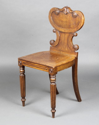 A Regency mahogany hall chair with shaped back and solid seat raised on turned and fluted supports 