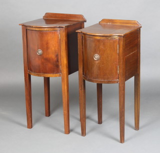A pair of Georgian style mahogany bow front bedside cabinets with raised backs fitted a cupboard enclosed by a panelled door, raised on square tapered supports 75cm x 33cm x 38cm 