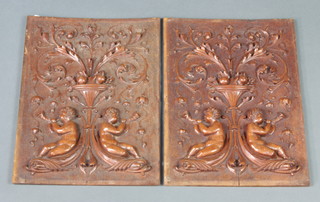 A pair of carved walnut panels decorated cherubs beneath an urn of fruit 38cm x 28cm 