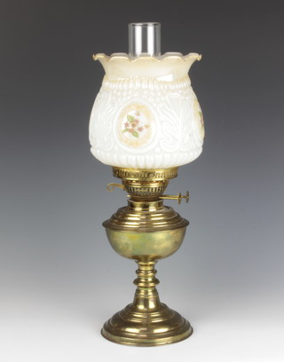 A brass oil lamp with clear glass chimney and an opaque glass shade 