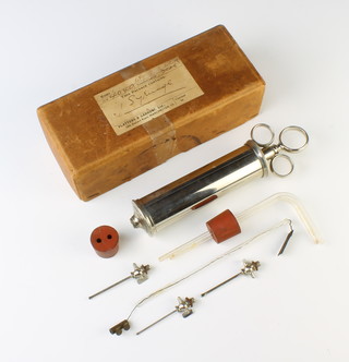 A chrome syringe contained in a cardboard box 