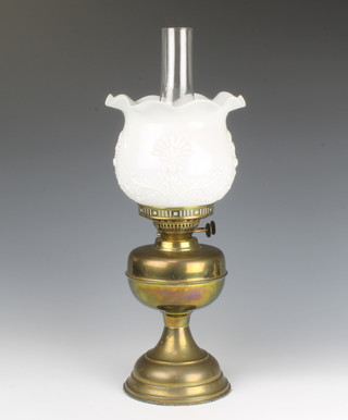 A brassed oil lamp with opaque glass shade and chimney