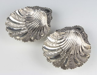 A pair of Victorian silver shell shaped butter dishes with repousse floral and scroll decoration Sheffield 1890, 13cm, 140 grams 