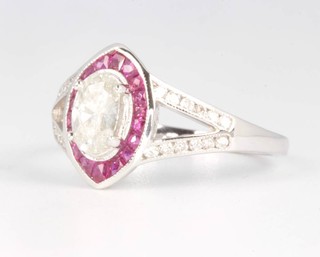 An 18ct white gold ruby and diamond ring, the centre oval cut diamond approx. 0.58ct surrounded by rubies with an open shank set with diamonds,  size M  