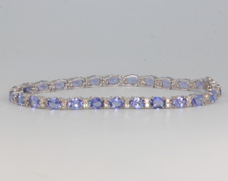 An 18ct white gold tanzanite and diamond line bracelet, the tanzanites approx. 9.2ct, diamonds approx 0.65ct, 17.5cm