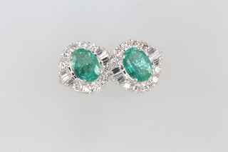 A pair of 18ct white gold emerald and diamond cluster earrings, the emeralds approx. 2.07ct surrounded by baguette diamonds 0.3ct and brilliant cut diamonds 0.81ct 
