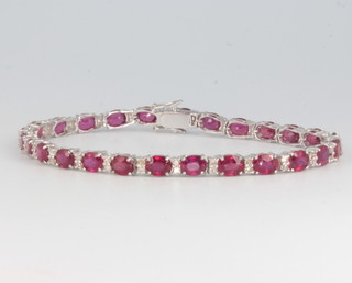 An 18ct white gold colour treated ruby and diamond line bracelet, the rubies approx. 13.3ct, the diamonds approx. 0.65ct, 17.5cm 