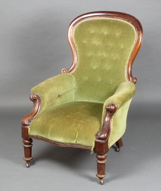 A Victorian mahogany show frame armchair upholstered in green buttoned material, raised on turned supports 