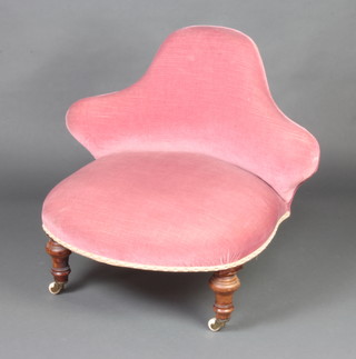 A Victorian nursing chair with shaped back, upholstered in rose pink material raised on turned supports 