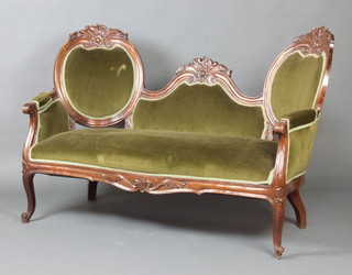 A Victorian carved mahogany show frame double spoon back settee upholstered in green material raised on cabriole supports 104cm h x 145cm w x 72cm d 