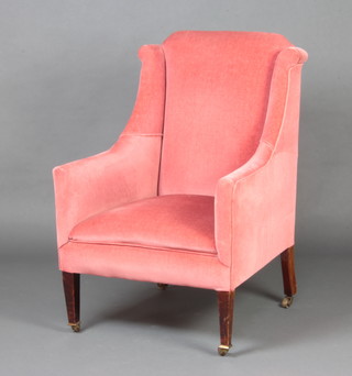 An Edwardian winged armchair upholstered in rose pink velvet, raised on square tapered  supports 