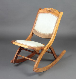 A Victorian carved and bleached mahogany folding campaign rocking chair, the seat and back upholstered in green material 