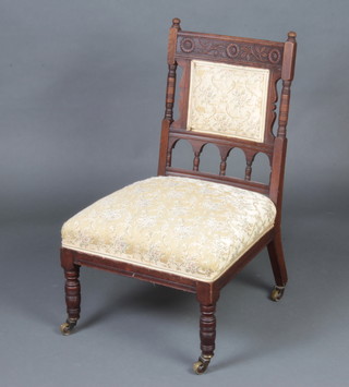 A late Victorian carved walnut nursing chair with upholstered seat and back, raised on turned supports 