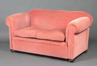 A Victorian drop arm Chesterfield upholstered in rose pink material, raised on bun feet 75cm h x 151cm w x 84cm d 