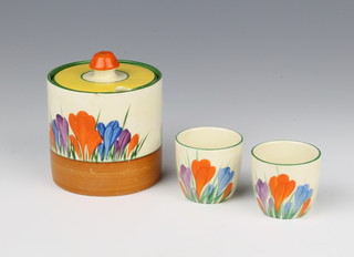 A Clarice Cliff Bizarre crocus pattern cylindrical preserve pot and lid 9cm and a pair of ditto egg cups 4cm  