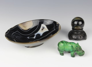 A carved malachite figure of a walking hippopotamus 4cm x 6cm, a carved and polished hardstone boat shaped bowl 5cm x 17cm x 11cm, a carved polished figure on a hardwood stand 3cm 