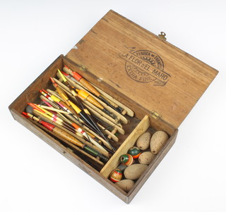 A wooden box containing a collection of vintage fishing floats and winders 