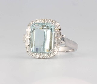 An 18ct white gold aquamarine and diamond cluster ring, the emerald cut centre stone approx. 5.65ct surrounded by brilliant and baguette cut diamonds approx. 0.95ct, size N 1/2