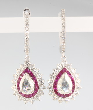 A pair of white gold ruby and diamond drop earrings, the pear cut diamonds 1.23ct, the rubies 1.37ct, brilliant cut diamonds 1.49ct 