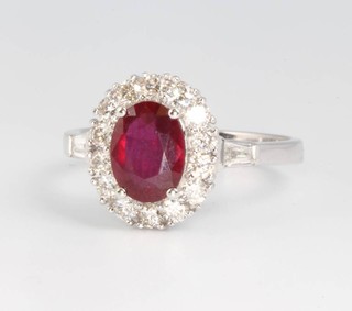 An 18ct white gold oval ruby and diamond cluster ring, the treated centre stone approx. 1.6ct surrounded by brilliant and baguette cut diamonds approx. 0.65ct, size N 