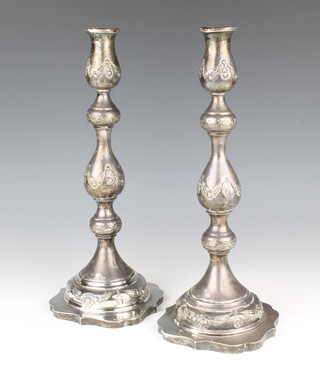 A pair of silver candlesticks with baluster stems with repousse floral and swag decoration, London 1923 36cm, 677 grams