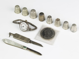 A lady's silver cased wrist watch, 8 silver thimbles, a Seagers Dry Gin fruit knife, a commemorative coin and a mother of pearl handled fruit knife 