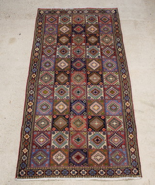 A red, green and blue ground rug, the centre formed of 55 square panels within a multi row border 290cm x 148cm 