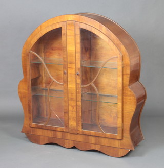 A 1930's Art Deco arched walnut display cabinet fitted adjustable shelves enclosed by astragal glazed panelled doors 131cm h x 122cm w x 32cm, marked to the back Registered RG design applied for 
