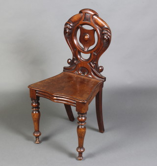 A Victorian mahogany hall chair with pierced shield shaped back and solid seat, raised on turned supports 