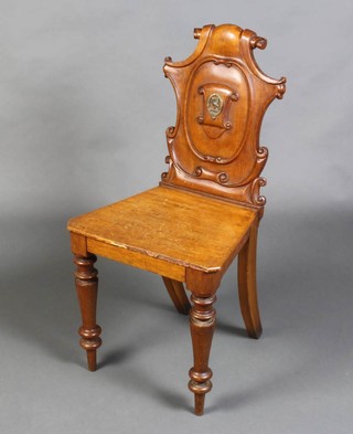 A Victorian oak hall chair with solid seat, the back with metal armorial badge, raised on turned supports 