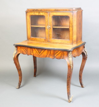 A 19th Century French inlaid walnut bonheur du jour, the raised back fitted cupboards enclosed by arched panelled doors, the base of serpentine outline fitted 1 long drawer, raised on cabriole supports with gilt metal mounts, 128cm h x 98cm w x 59cm d 