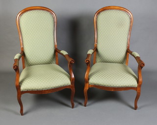 A pair of Victorian style beech open arm chairs the seats and backs upholstered in green material raised on cabriole supports