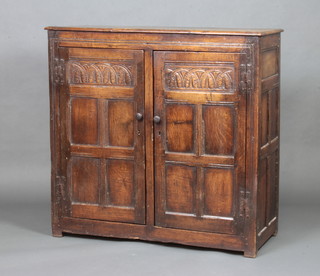 A 19th Century, 17th Century style carved oak cupboard enclosed by panelled doors, the top formed of 3 planks, 104cm h x 107cm w x 48cm d 