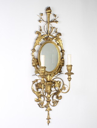 A Regency style oval plate wall mirror contained in a gilt painted metal carved wood frame with sconces to the sides 94cm x 29cm 