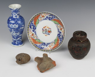 A Japanese shallow dish with border of flowers enclosing flowers beside a pond 19cm, a baluster prunus vase 20cm, an over decorated ginger jar and cover, a Roman oil lamp and miniature clay portrait bust 