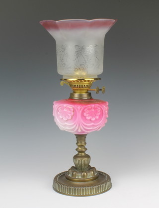 A Victorian pink opaque glass oil lamp reservoir raised on an embossed brass base together with an associated shade 