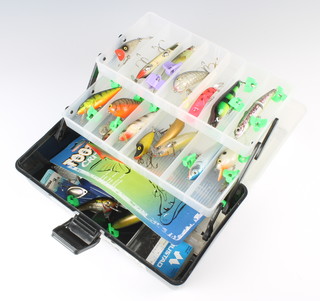 A cantilever box containing a collection of fishing lures and mustad treble hooks, some wooden and others 