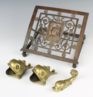 A Victorian gilt metal adjustable book rest, the centre decorated a portrait of Queen Victoria marked T and T, raised on bun feet (f) 24cm, 2 brass spoon warmers in the form of fish 7cm, a brass weight in the form of a dolphin 9cm 