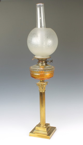 A Victorian clear glass oil lamp reservoir raised on a brass reeded column with Corinthian capital and stepped base complete with etched glass chimney and shade
