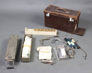 A midwife's  rectangular leather bag containing a collection of medical instruments 
