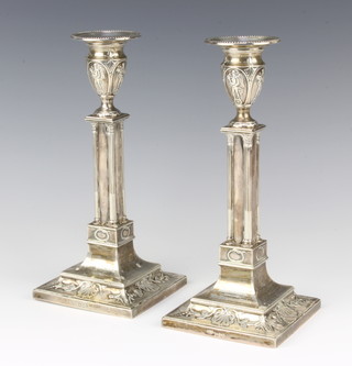 A pair of Edwardian silver candlesticks with quadruple column stems on spread bases with shell decoration, London 1903, maker Goldsmiths and Silversmiths Company Ltd. 24cm 