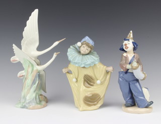 A Nao figure of a curtseying clown 19cm and other of a clown playing an accordion 21cm and a Nao figure group of cranes 27cm 
 