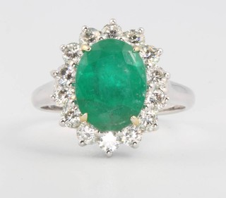 An 18ct white gold oval cut emerald and diamond cluster ring, the centre stone approx. 3ct surrounded by brilliant cut diamonds 1ct, size M 