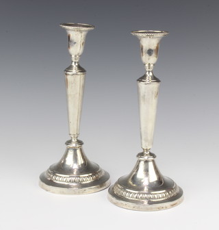 A pair of early 20th Century Continental silver candlesticks of tapered form with vacant cartouches, weighted, 24cm 