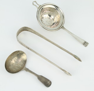 A George IV silver caddy spoon with engraved decoration of a bird amongst flowers, tea strainer and sugar tongs, 76 grams